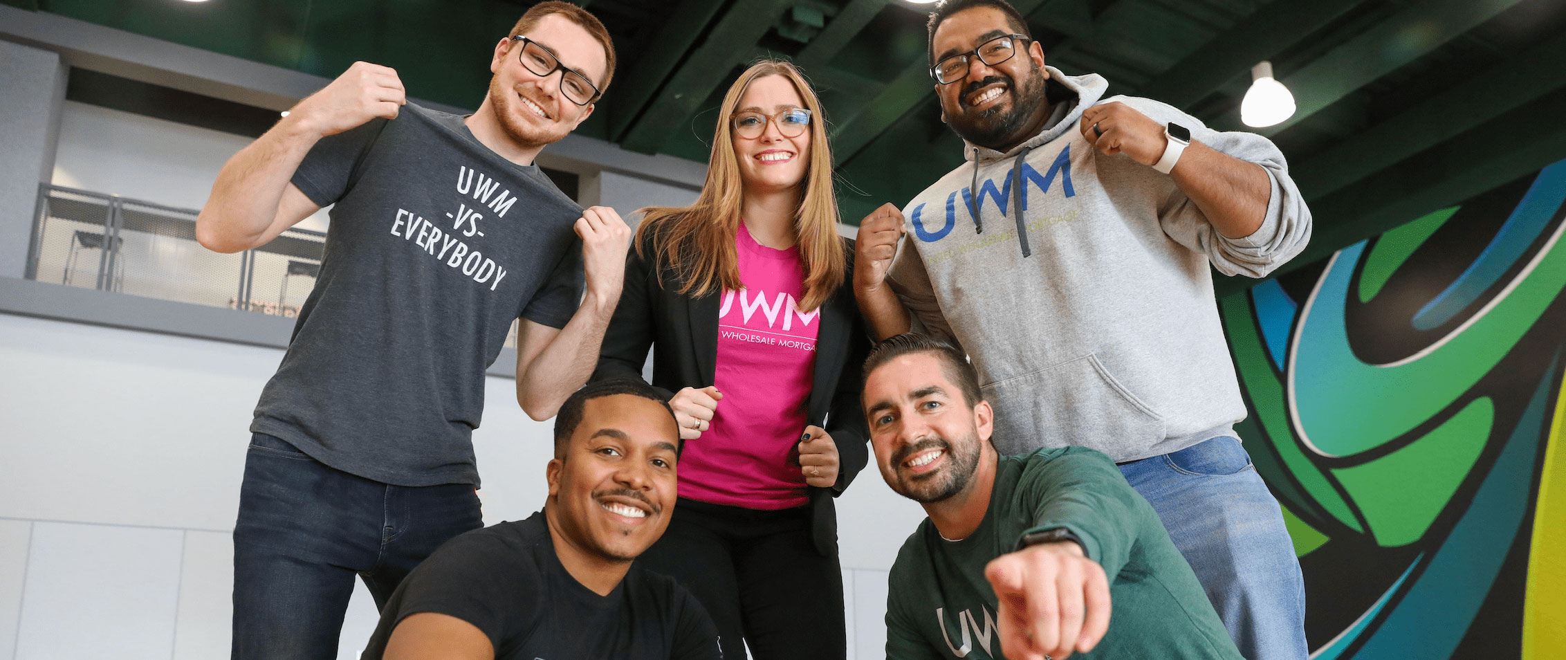 UWM team members posing with merch on the basketball court